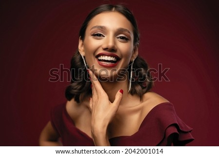 Beautiful model girl with elegant hairstyle in red dress. Woman with red lips and nails. Cosmetics, beauty and manicure on nails