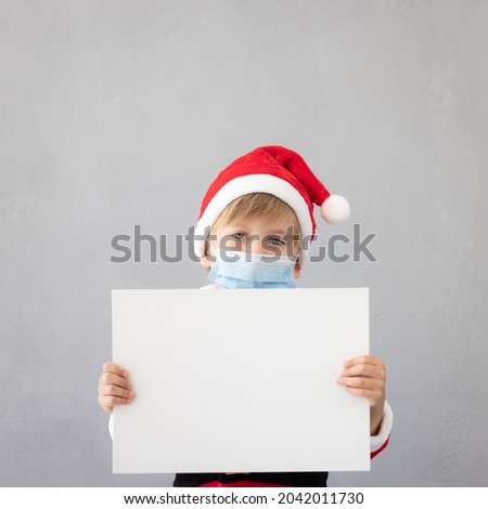 Portrait of child wearing medical mask. Kid holding banner blank with copy space. Christmas holiday during coronavirus covid-19 pandemic concept