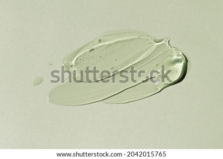 Liquid gel smear isolated on grey green background. Beauty cosmetic smudge such as pure transparent aloe lotion, facial jelly serum, cleanser, shower gel or shampoo top view. Royalty-Free Stock Photo #2042015765