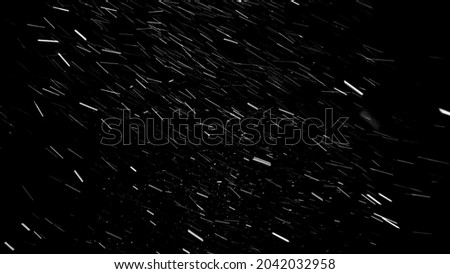 Heavy snow falling from left to right on the black background. Severe blizzard with strong wind and a lot of snow falling almost horizontally.