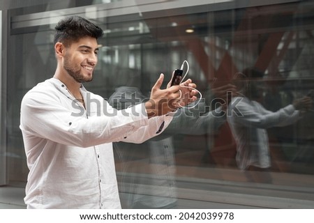 Young man smiling happy doing video call using smartphone at city. High quality photo