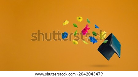 Black wallet with spring flowers flying on a green background with copy space. Positive news, thinking and energy concept. Optimistic future, mood and atitude. Economy, gdp and sales growth concept. 