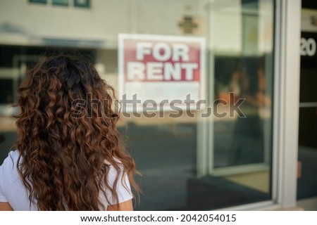 Back of woman standing in front of store with for rent sign.