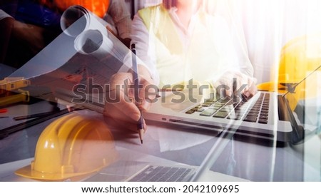 Two colleagues discussing data working and tablet, laptop with on on architectural project at construction site at desk in office