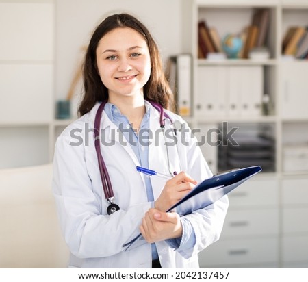Woman doctor wear white medical uniform and stethoscope with blue folder of documents in clinic