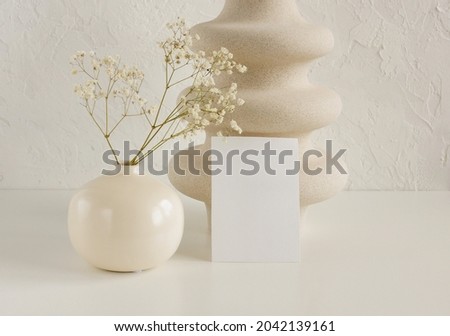 Blank paper business mockup template and modern beige vasen with dry flowers  on white desk with copy space.
Card Mockup,branding.
