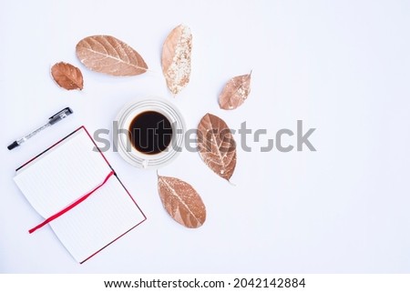 Autumn composition. Cup of coffee, dry leaves, book and pen on white background. Autumn, autumn concept. Flat lay, top view, copy space
