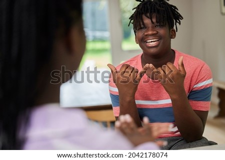 Teenage Boy And Girl Having Conversation Using Sign Language At Home