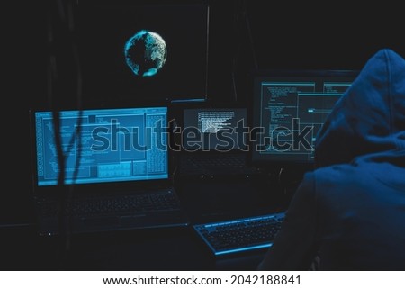 Cyber criminal hacking system at monitors, hacker attack web servers in dark room at computer with monitors sending virus using email vulneraility. Internet crime, hacking and malware concept. Royalty-Free Stock Photo #2042188841