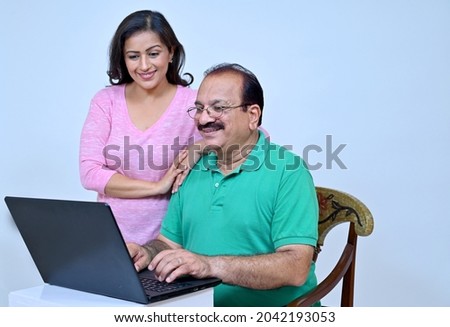 Senior man doing online shopping with debit card with daughter at home , studio shot Royalty-Free Stock Photo #2042193053