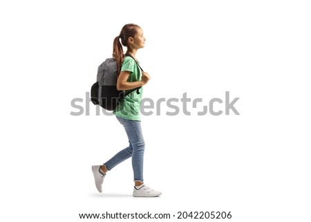 Full length profile shot of a girl carrying a backpack and walking isolated on white background