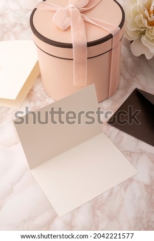 Vertical image of pink present box with ribbon,decorative flower.envelope on the desk 