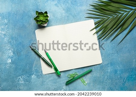 Composition with notebook, stationery, palm leaf and houseplant on color background
