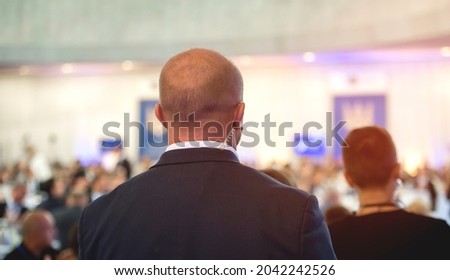 Security guard standingon public meeting. Mature security guard listening to earpiece against crowd. Secret service agent listening to his earpiece, side. secret service agent.