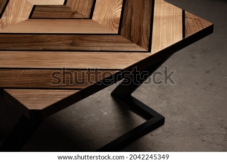 Expensive vintage furniture. The table is covered with epoxy resin and varnished. Luxury quality wood processing. Wooden table on a dark background. Swirling geometric patterns in the form of a maze.