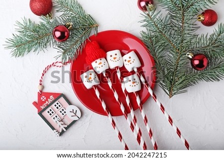 Plate with snowmen made of soft marshmallows and Christmas decor on light background