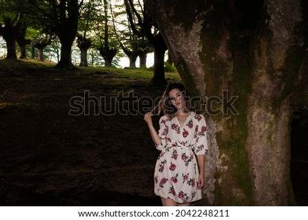 brunette woman in a floral dress in a beech forest of the basque country