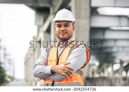 Asian engineer handsome man or architect looking construction with white safety helmet in construction site. Standing at highway concrete road site. Royalty-Free Stock Photo #2042254736