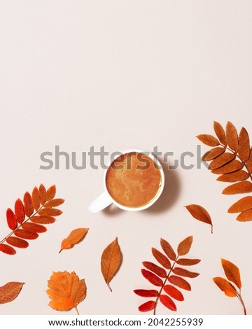 Cup of coffee with milk and red autumn leaves on pastel pink paper background. Autumn, fall composition, monohrome flat lay, top view, copy space.