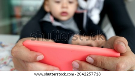 Close-up mother hands holding cellphone watching content online with toddler child