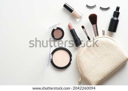Make-up cosmetic bag white background. Glamour makeup artist pouch with beauty products. Flat lay, top view Royalty-Free Stock Photo #2042260094