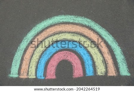 Child's chalk drawing of rainbow on asphalt, top view