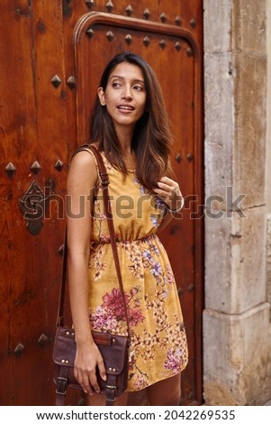 Elegant lady leaning on a door fully while gently holding her hair
