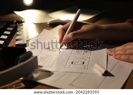 Woman drawing cartoon sketches at workplace, closeup. Pre-production process Royalty-Free Stock Photo #2042283395