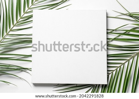 Blank poster and palm leaves on white background