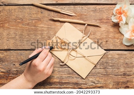 Woman with envelope writing text LAVENDER LAVANDULA on wooden background