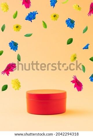 Red gift box as a stand with colorful spring flowers flying on a orange background. Optimistic message and news announcement concept. Positive product presentation. Advertisement idea. 3D illustration