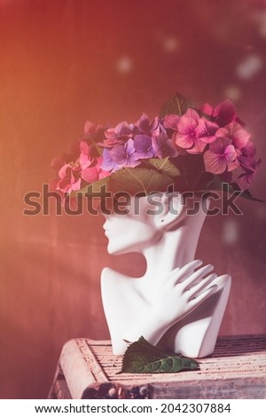 Fresh bunch of colorful hydrangea in vase in shape of womens face on dark background. Trendy Ceramic Vase of human head, Handmade Modern Statue Art Flower Vase. Card Concept, copy space for text Royalty-Free Stock Photo #2042307884