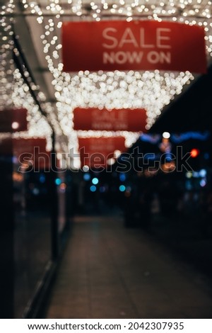 White abstract bokeh made from buildings and christmas lights on black isolated background. Blurred street and shops. Red Sale now on sign. Holiday concept, blur bokeh, overlay for your images.