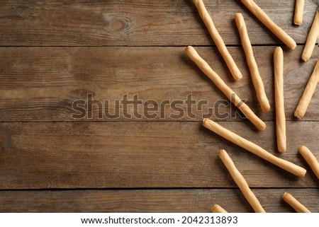 Delicious grissini sticks on wooden table, flat lay. Space for text