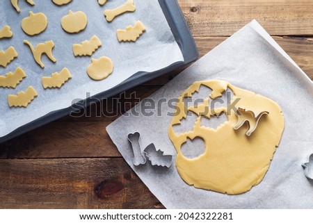 Cookies in various shapes for Halloween on a baking sheet. Cookies cut before baking. Copy space.