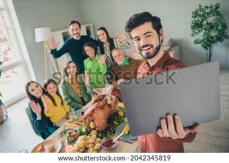 Photo of adorable funny family celebrating thanks giving day sitting table talking modern device smiling indoors room home