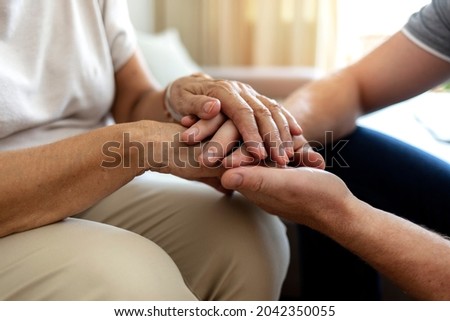 Cropped shot of an unrecognizable male nurse holding his senior patient's hand in comfort. Mother and son hands holding together in love and support after losing loved ones amid coronavirus outbreak. Royalty-Free Stock Photo #2042350055