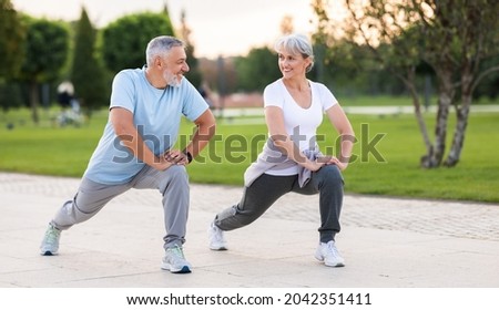 Energize your morning. Full length of active happy elderly family couple in sportswear working out together in city park in morning. Joyful senior husband and wife making sport outdoors, warming up Royalty-Free Stock Photo #2042351411