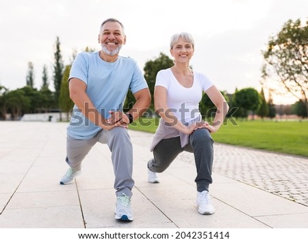 Energize your morning. Full length of active happy elderly family couple in sportswear working out together in city park in morning. Joyful senior husband and wife making sport outdoors, warming up Royalty-Free Stock Photo #2042351414