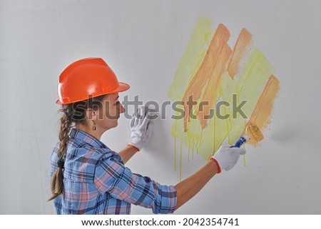 painter in white gloves paints the wall