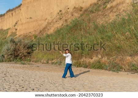 Cute teenage girl or woman wearing blue pants, white shirt, white bandana on the beach nature landscape fresh air beach. Natural beauty. lifestyle, real people, funny, dance.