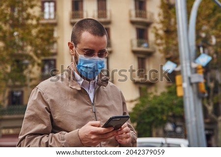 An actively intrigued man looking at his phone texting while standing in the street