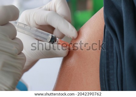 Close up Doctor injecting COVID-19 vaccine on a person's shoulder, Vaccination, immunization, disease prevention concept