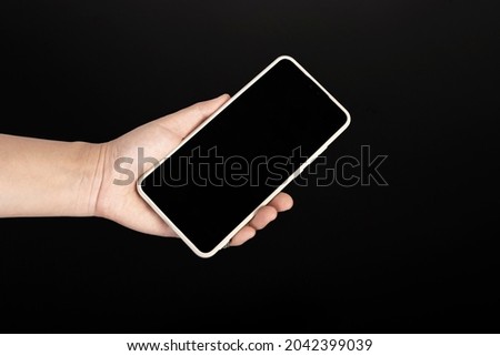 A woman's hand holding a cell phone isolated on a black background