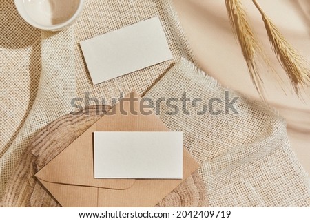 Flat lay of creative interior composition with mock up visit cards, textile, rocks, wood, natural materials, dry plants and personal accessories. Neutral colors, top view, template.
