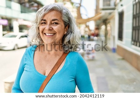 Middle age grey-haired woman smiling happy standing at the city.