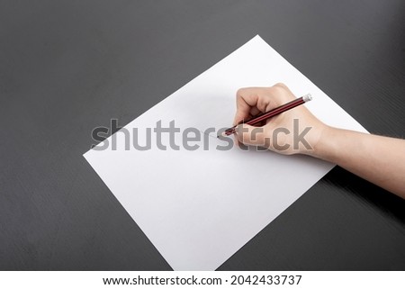 A woman's hand writes on a blank piece of paper