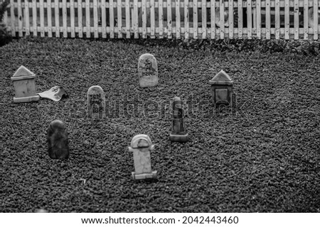 Black and white closeup of tiny model gravestones in a graveyard at a model village