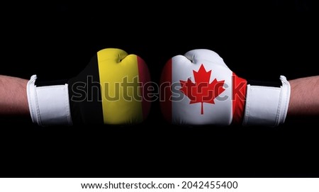 Two hands of wearing boxing gloves with Canada and Belgium flag. Boxing competition concept. Confrontation between two countries