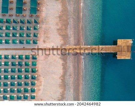 Top view of the beach with sun loungers and umbrellas. There is no one, the sea is calm in the morning light, drone aerial photo
